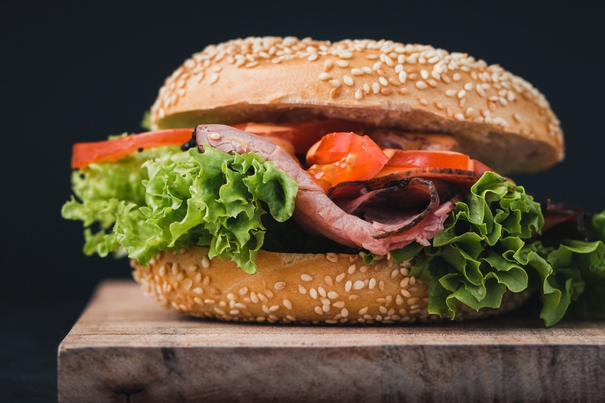 Bánh mì vòng sandwich cá hồi hun khói, xà lách và cà chua trên thớt gỗ, món ăn sáng hoặc bữa trưa lý tưởng
