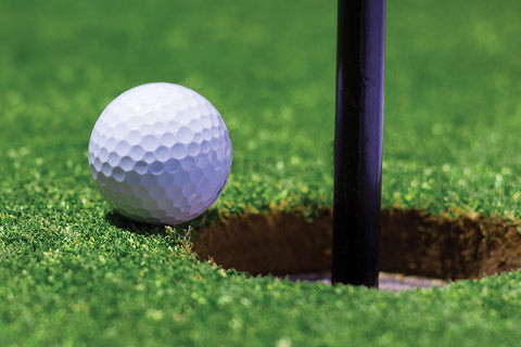 So sánh bóng golf mềm và bóng golf cứng cạnh lỗ golf, minh họa sự khác biệt