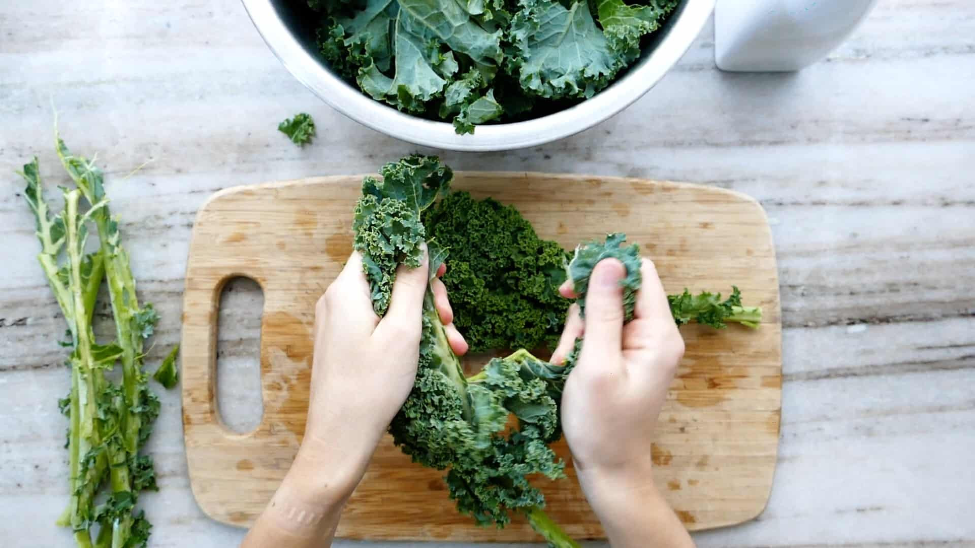 Người phụ nữ đang xé lá cải xoăn khỏi cuống trên thớt