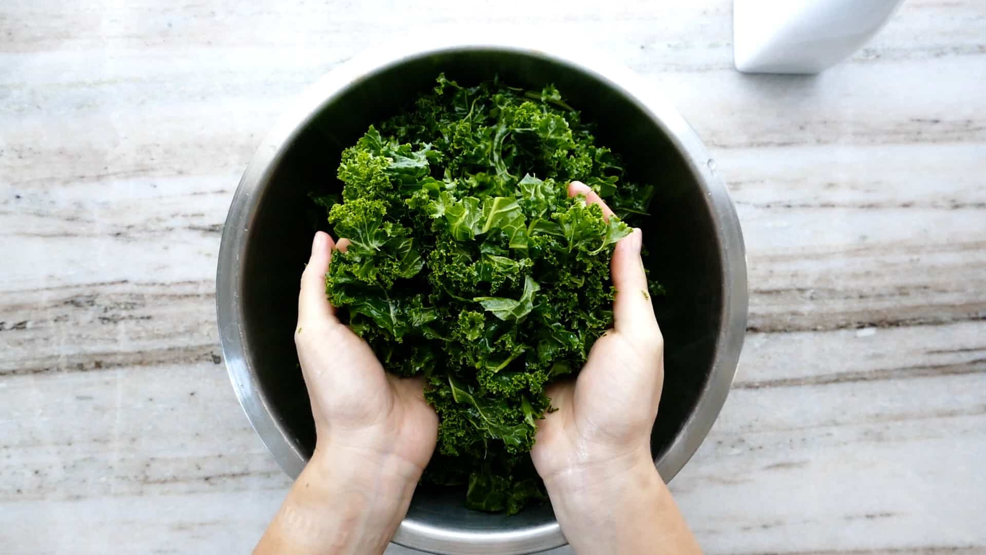 Người phụ nữ cầm lá cải xoăn đã xoa bóp trên lòng bàn tay
