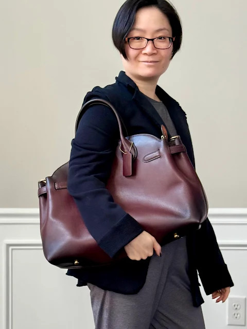 Hình ảnh người mẫu đeo túi Coach Empire 40 Merlot với dây đeo vai có thể điều chỉnh