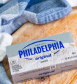 Một khối phô mai kem Philadelphia vẫn còn trong giấy gói và hộp, minh họa cách bảo quản phô mai kem đúng cách để kéo dài thời gian sử dụng.