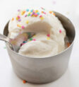 Spoon Taking a Bite out of a Metal Dish with Soft Serve Ice Cream.