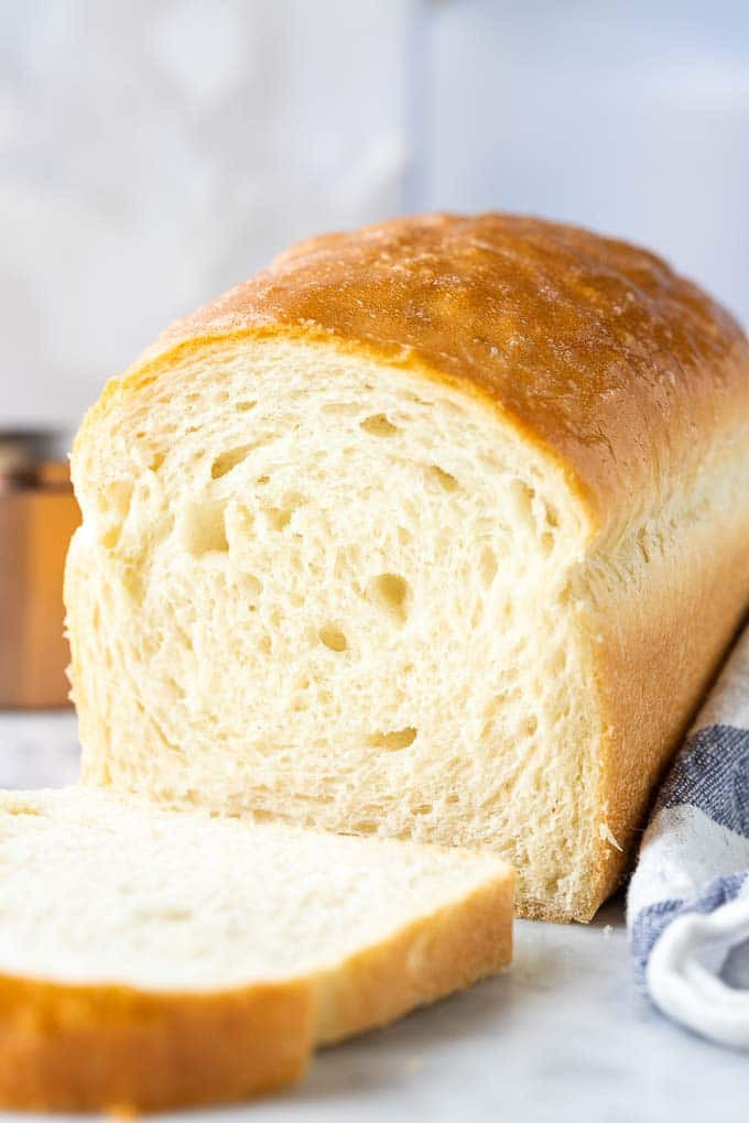 Bánh mì trắng với lát cắt đầu tiên bên cạnh một chiếc khăn ăn màu trắng và xanh lam